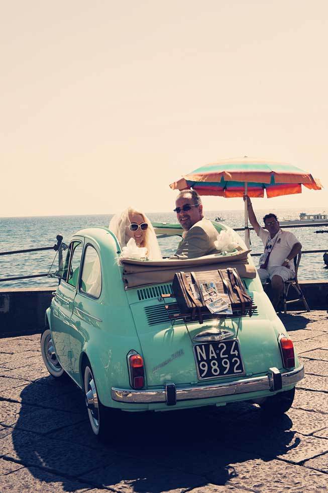 Bridal couple having fun on a vintage car in Atrani